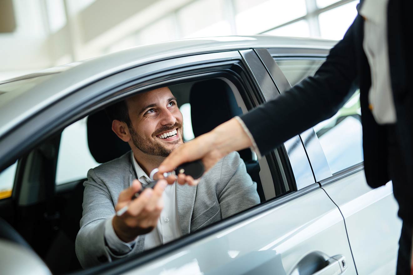 man taking the keys to new car while in drivers seat