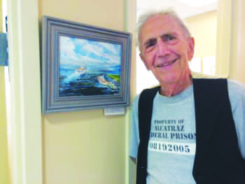 Greenwich resident and local artist Michael Spezzano stands in front of his artwork displayed at the First Bank of Greenwich during his first art show there.