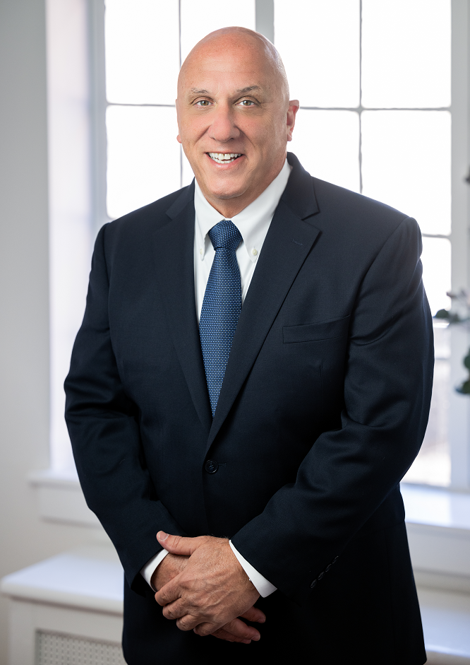 Image of Frank J. Gaudio, the Bank's President & CEO. smiling in front of a window with his hands folded in front of him.