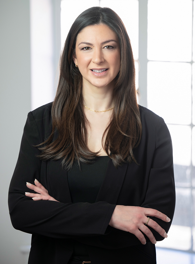 Image of Kaitlyn N. Carlucci, the Bank's SVP, Compliance & Risk Management, smiling in front of a window with her arms crossed in front of her.