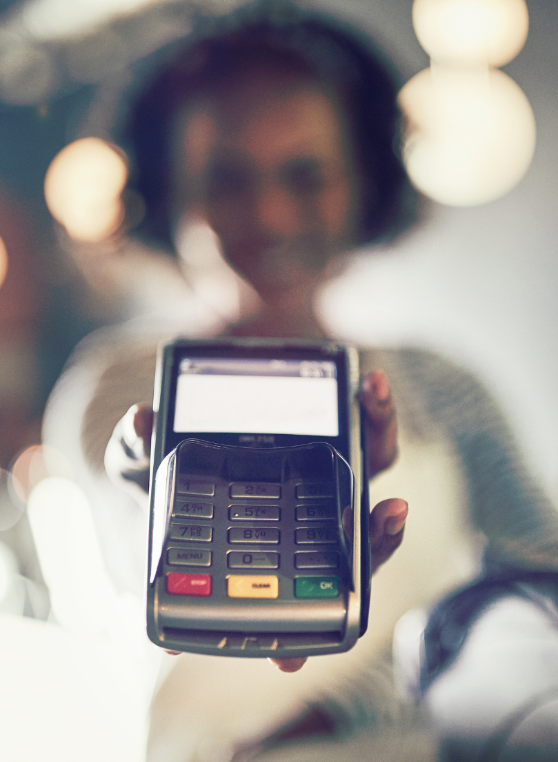 Blurry image of a woman holding out a credit card machine.