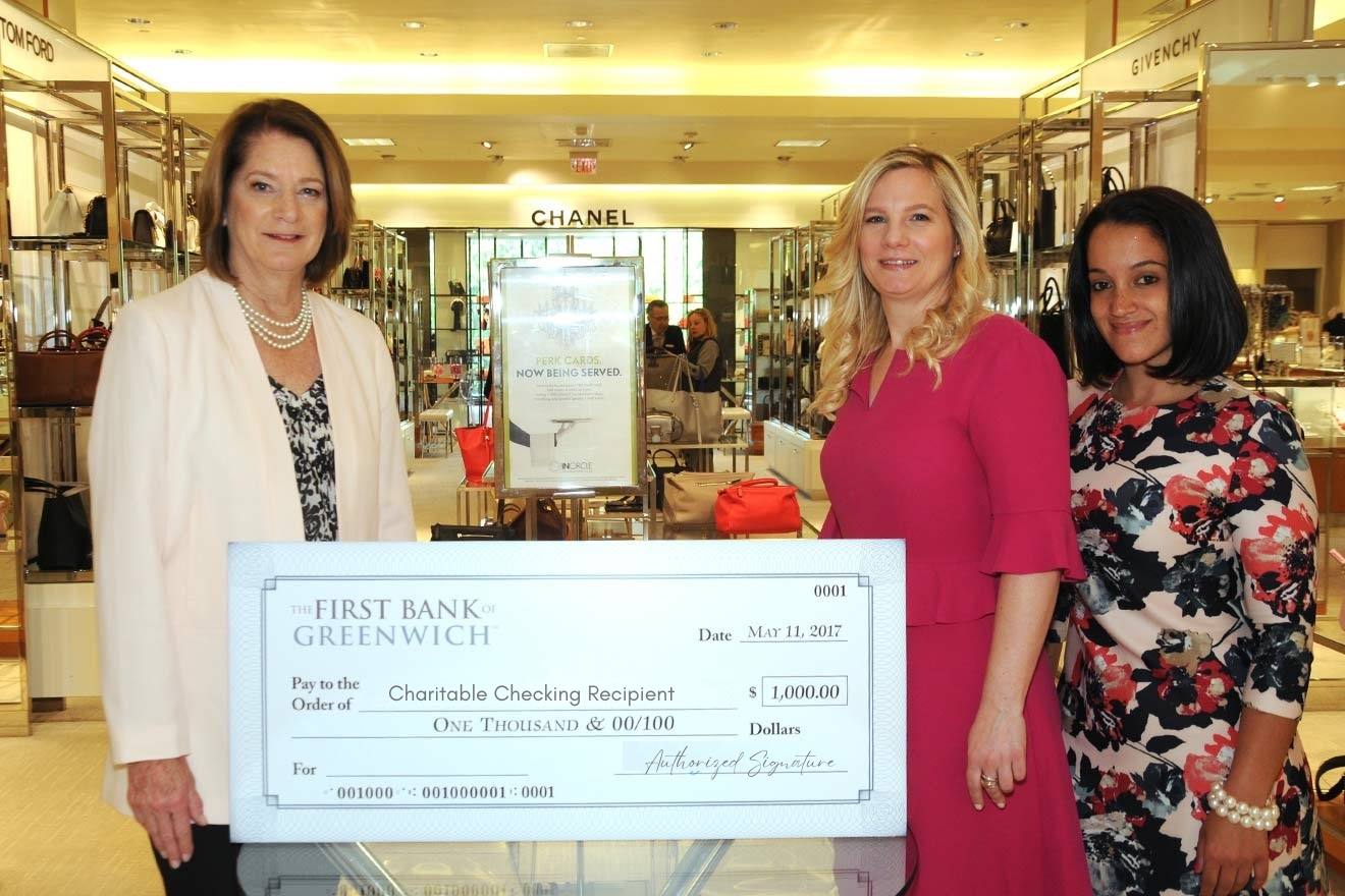 Bank staff presenting Charitable Checking award check to a recipient at an event in a department store.