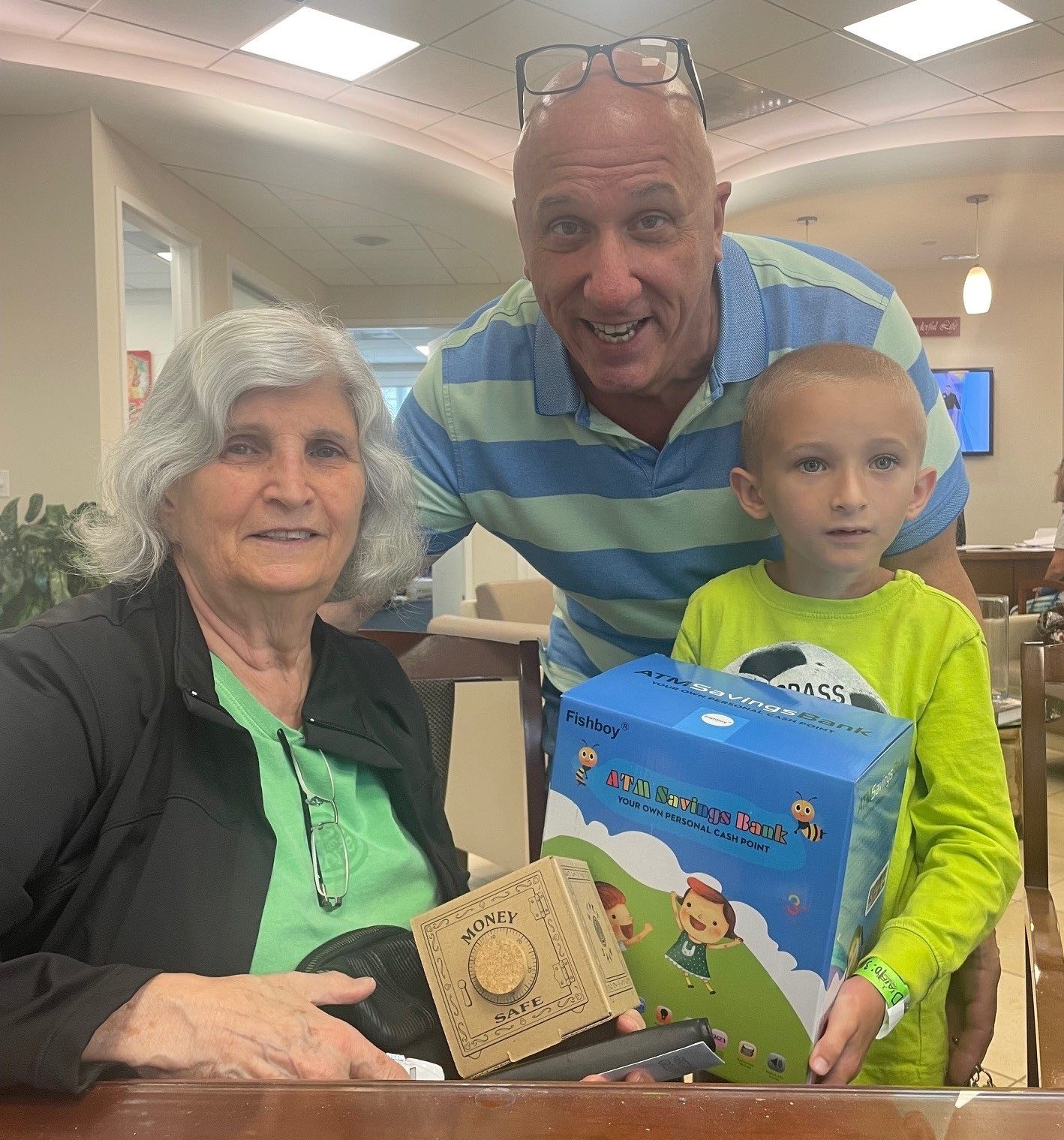 Image of the Bank President with a grandmother and grandson holding financial literacy products.